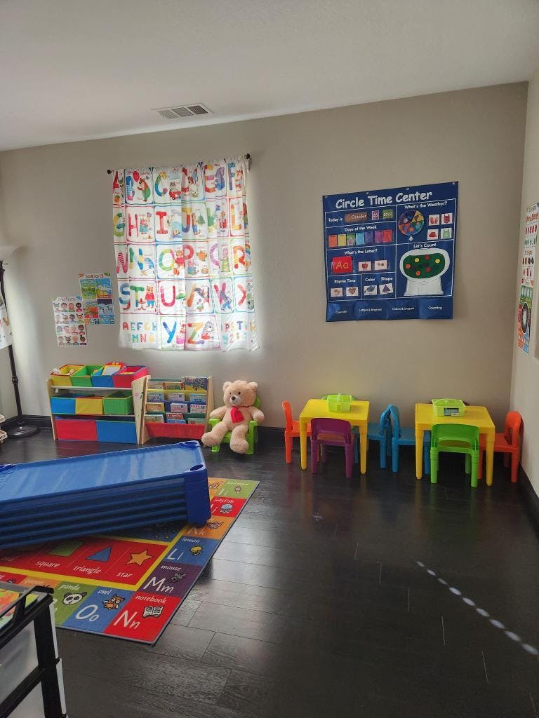 A classroom with colorful furniture, a teddy bear, and an alphabet curtain