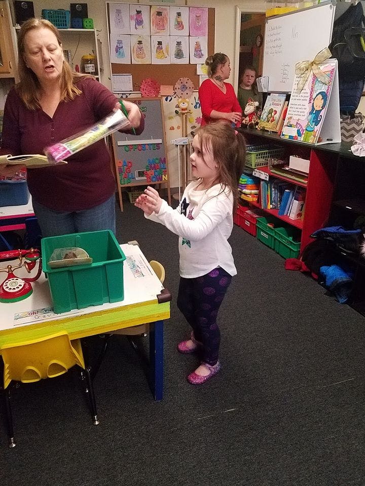 Adult holding an item for a child in a classroom