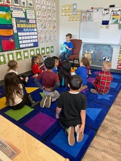 Children sitting on a colorful rug in a classroom