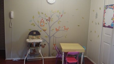 High chair and child's table with chairs in a room with tree wall decals