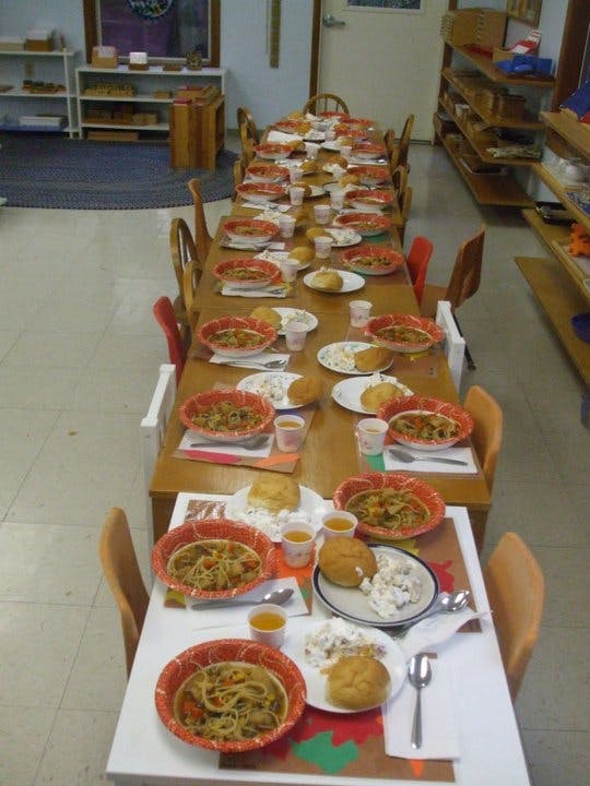 Long table set with multiple place settings of food in a classroom