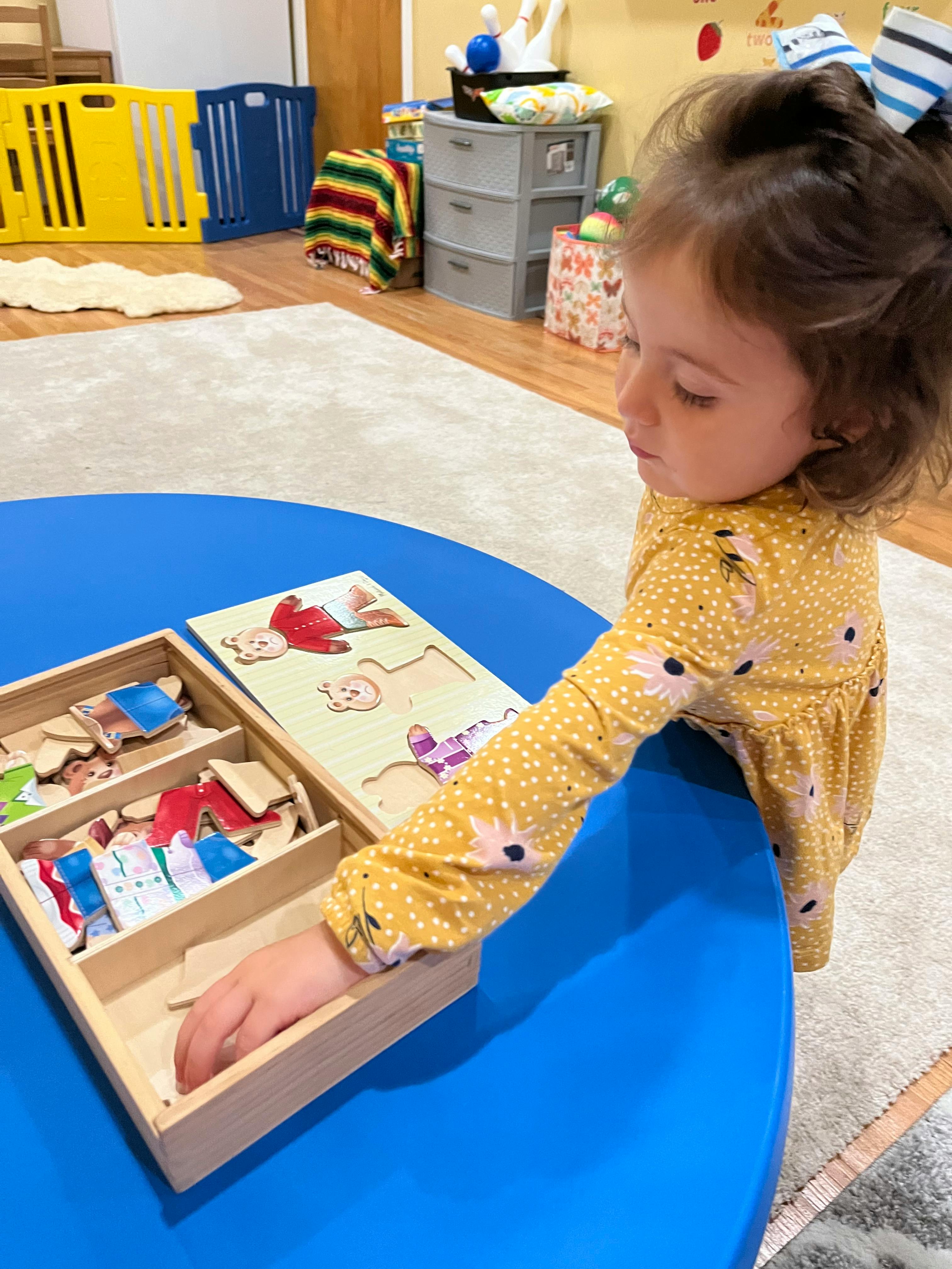 Child playing with a wooden puzzle on a blue table