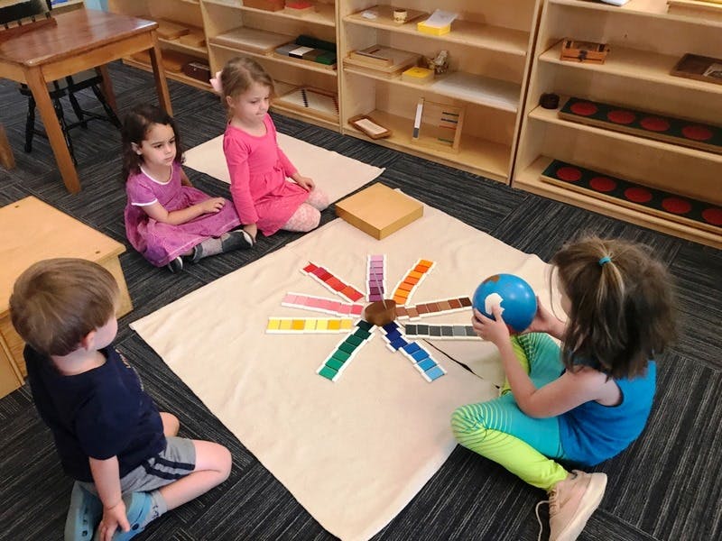 Four children sitting on the floor around a color matching activity
