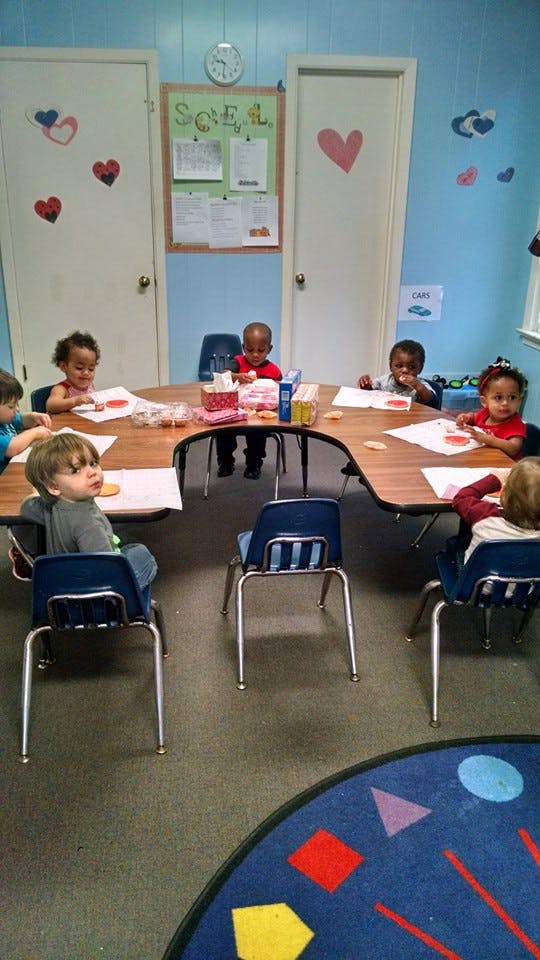 Children sitting at a U-shaped table in a classroom