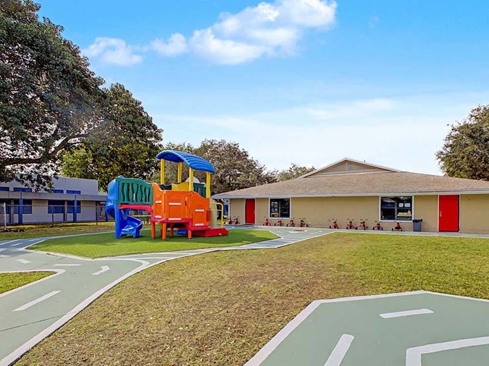 Colorful playground structure on grass with a tan building in the background