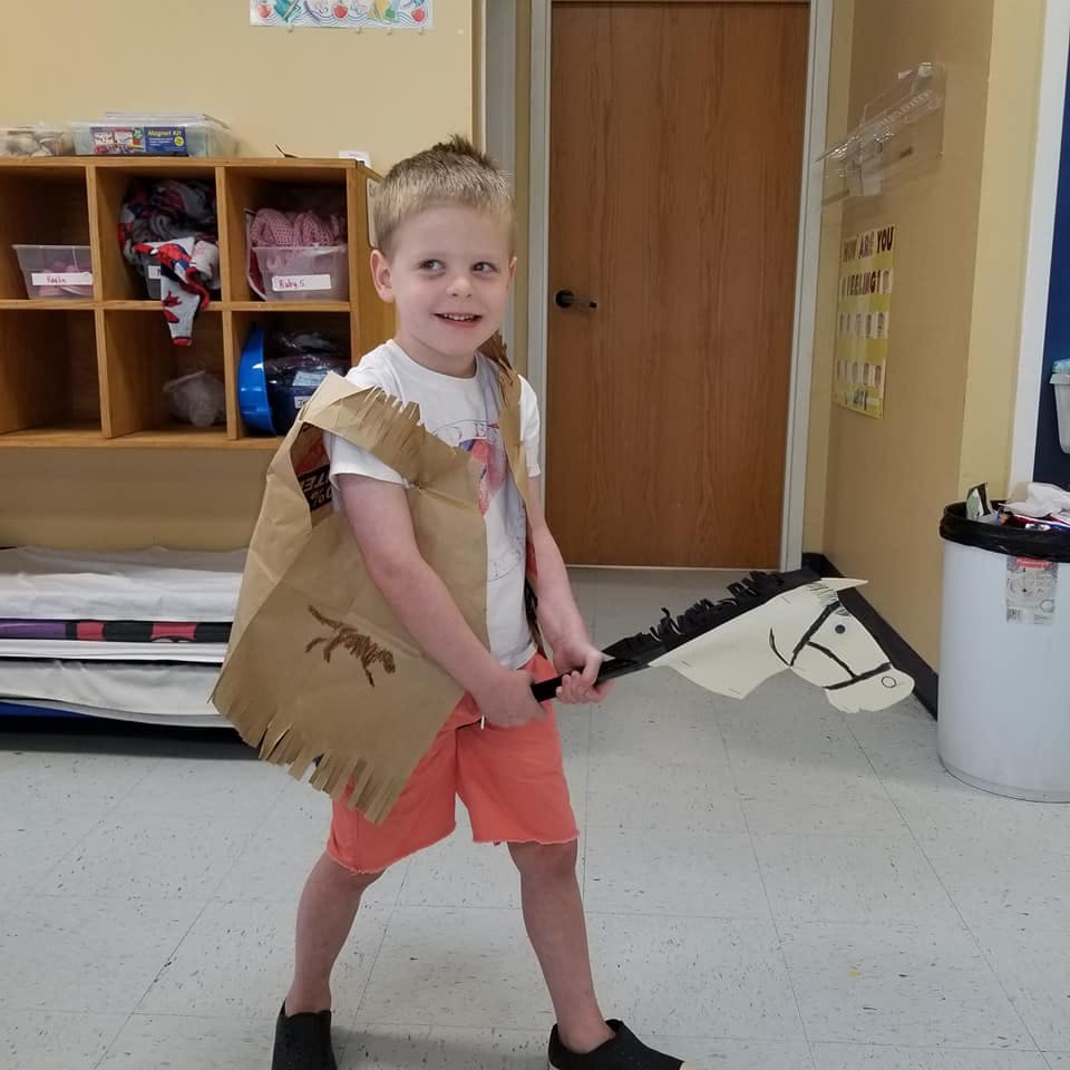 Child in a vest holding a hobby horse