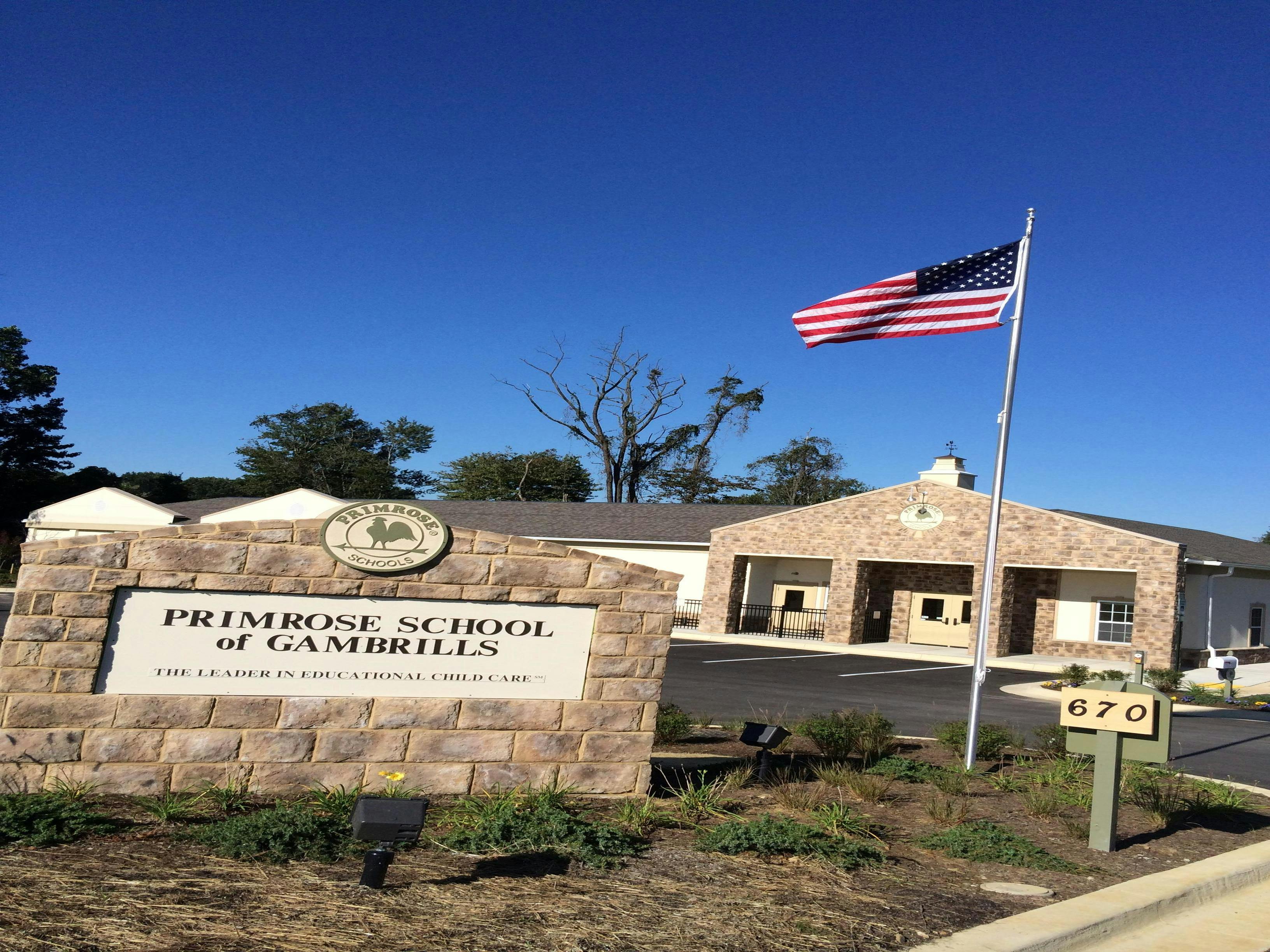 Primrose School of Gambrills sign with an American flag and building in background
