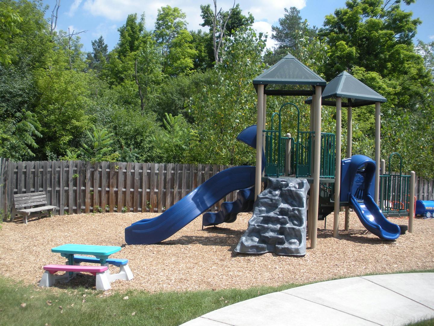 Playground with blue slides, climbing wall, and small picnic tables