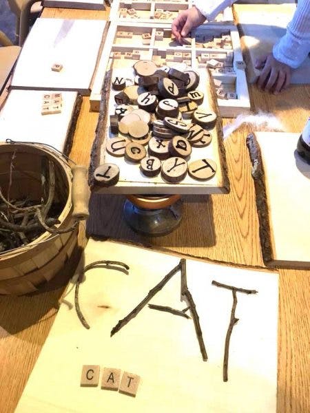 Person's hands arranging wooden letter tiles and sticks to spell words