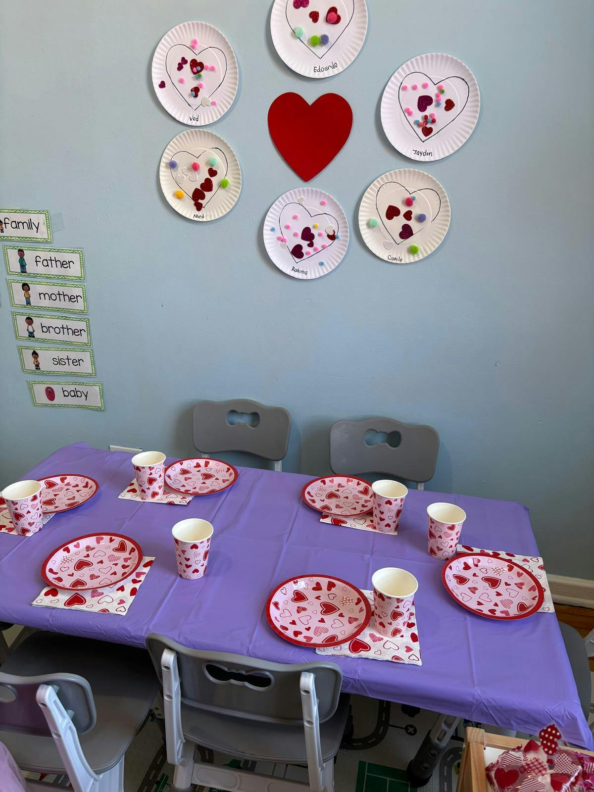 Classroom decorated with heart-themed crafts and a table set for a party