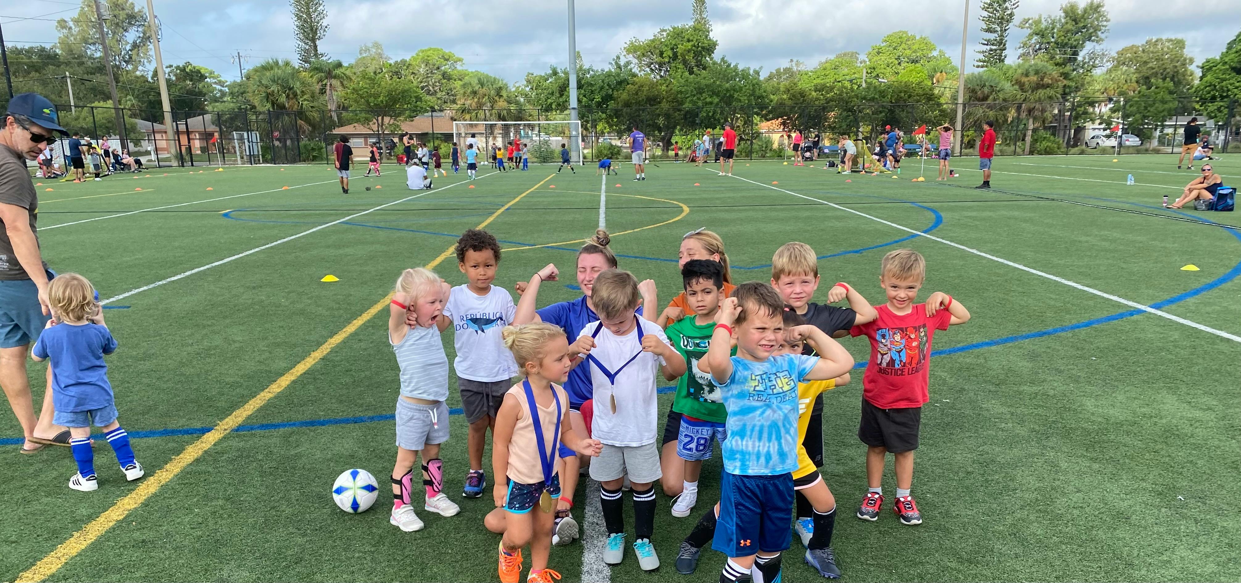 Group of children on a soccer field flexing their arms