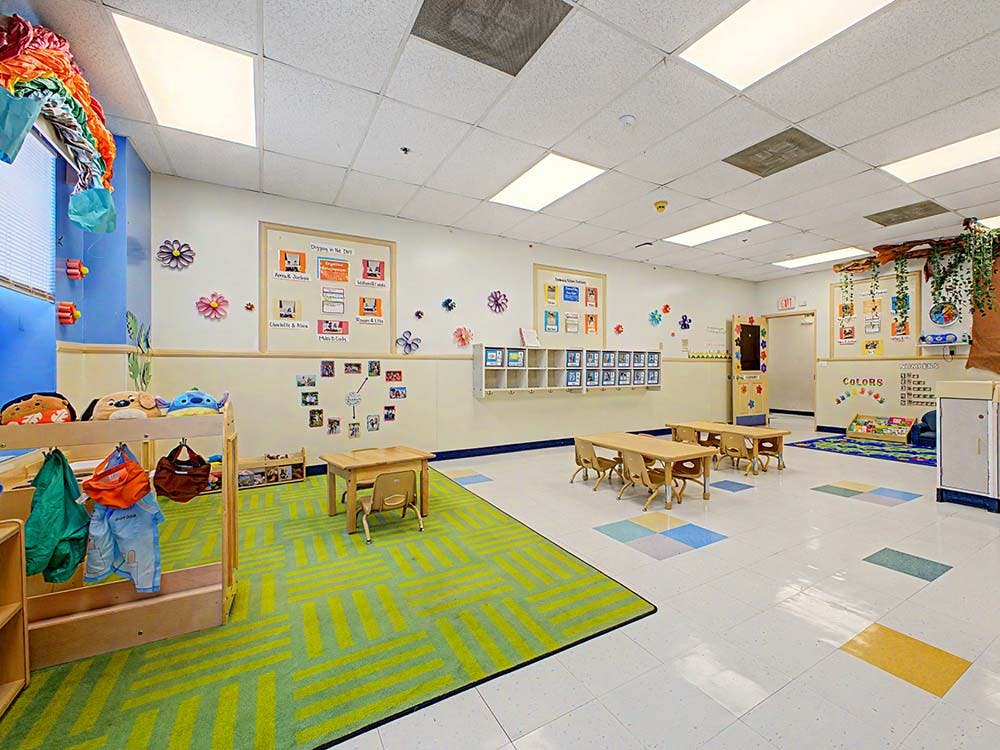 A colorful empty classroom with small tables, chairs, and play areas