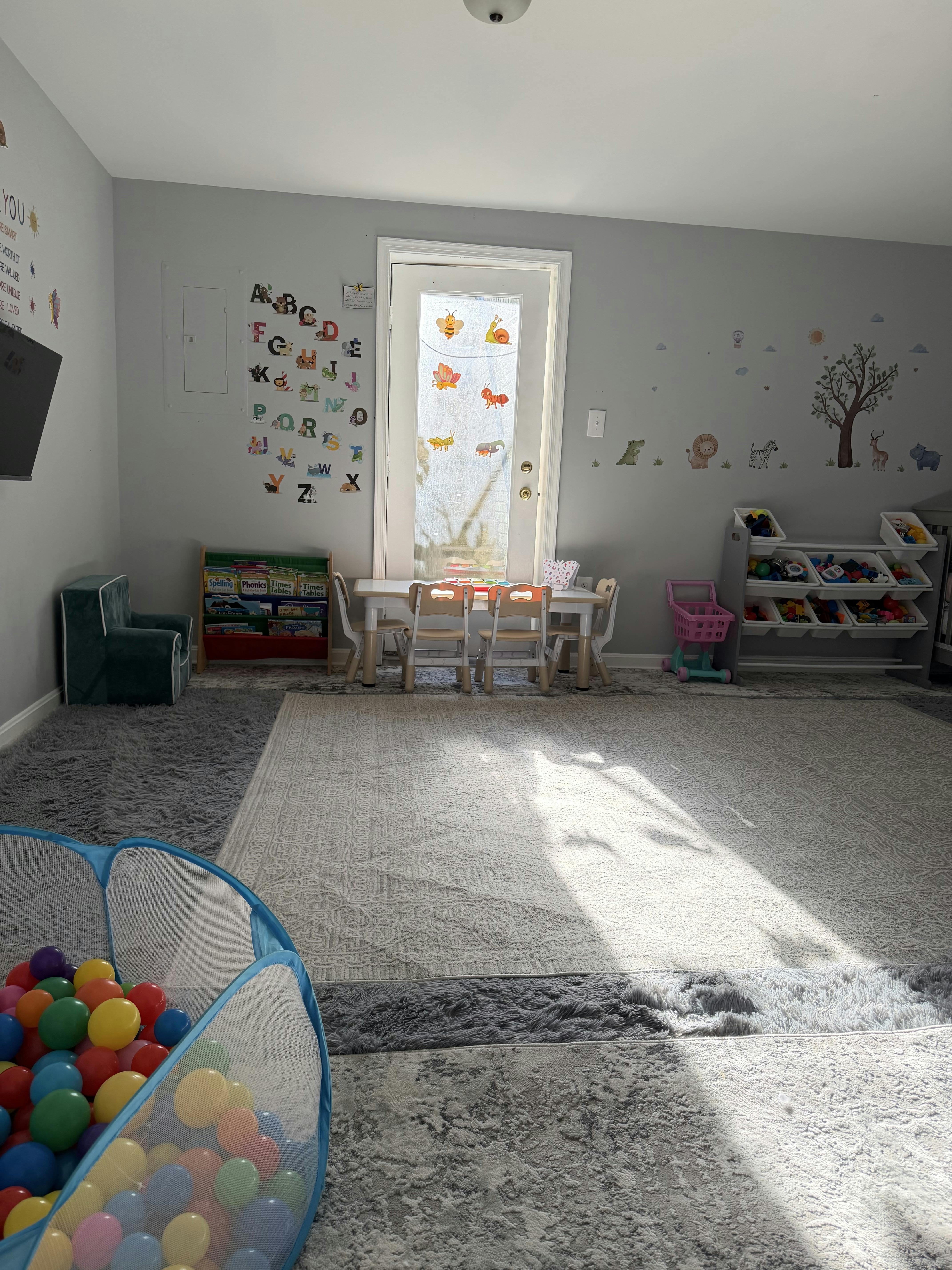A children's playroom with a table and chairs, bookshelves, and a ball pit