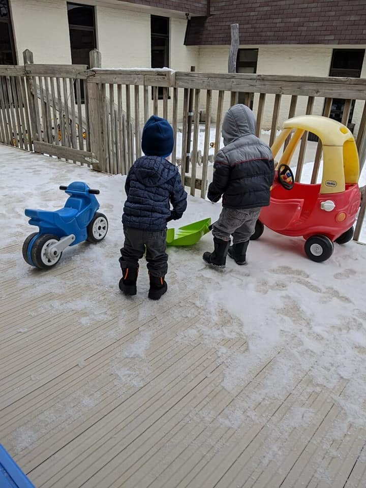 Two children playing with toys on a snowy deck