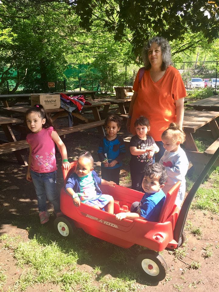 Adult and several children outdoors, two children in a red wagon