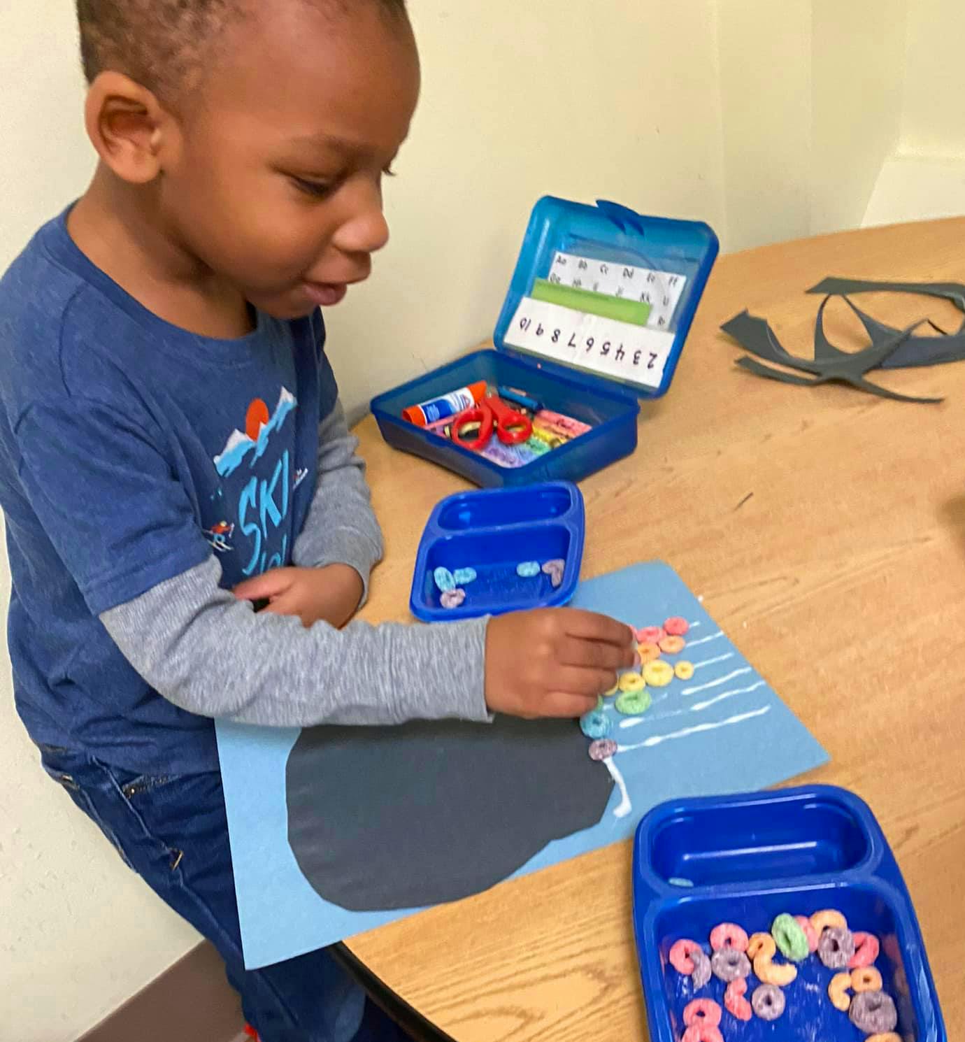 Child creating art with cereal pieces on paper