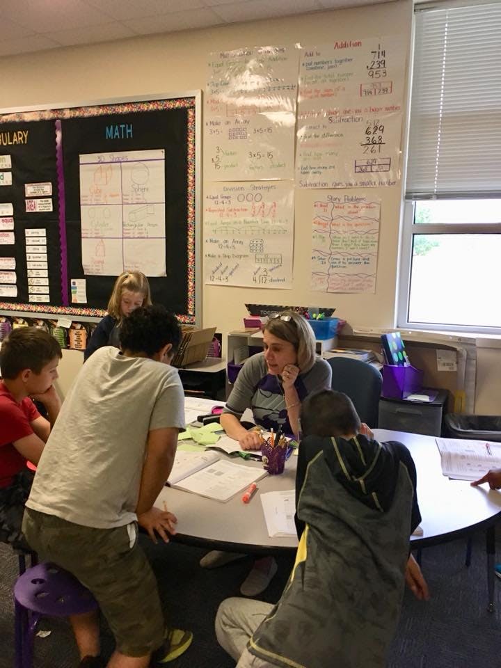 Adult and children gathered around a table in a classroom