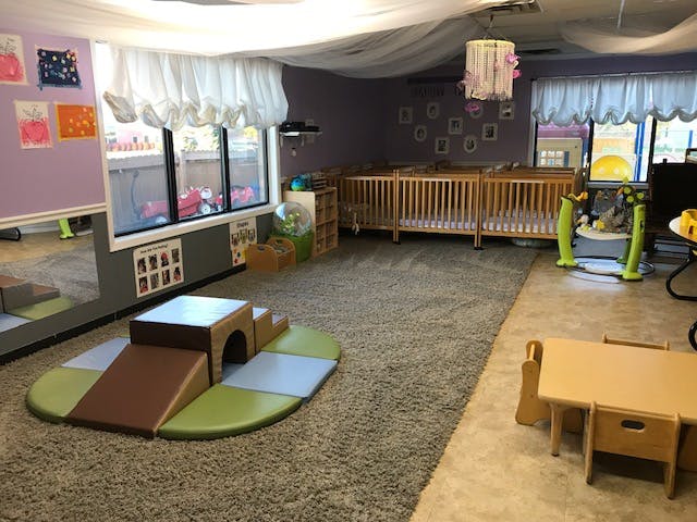 Playroom with soft play equipment, cribs, and small tables