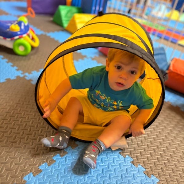 Child sitting inside a yellow play tunnel
