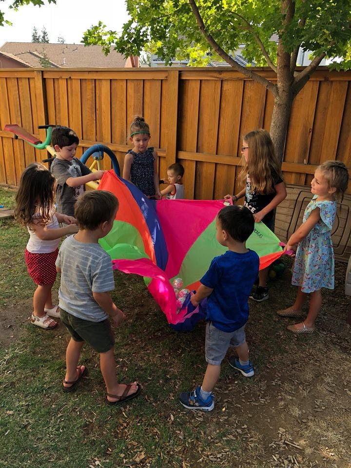 Children playing with a colorful parachute outdoors