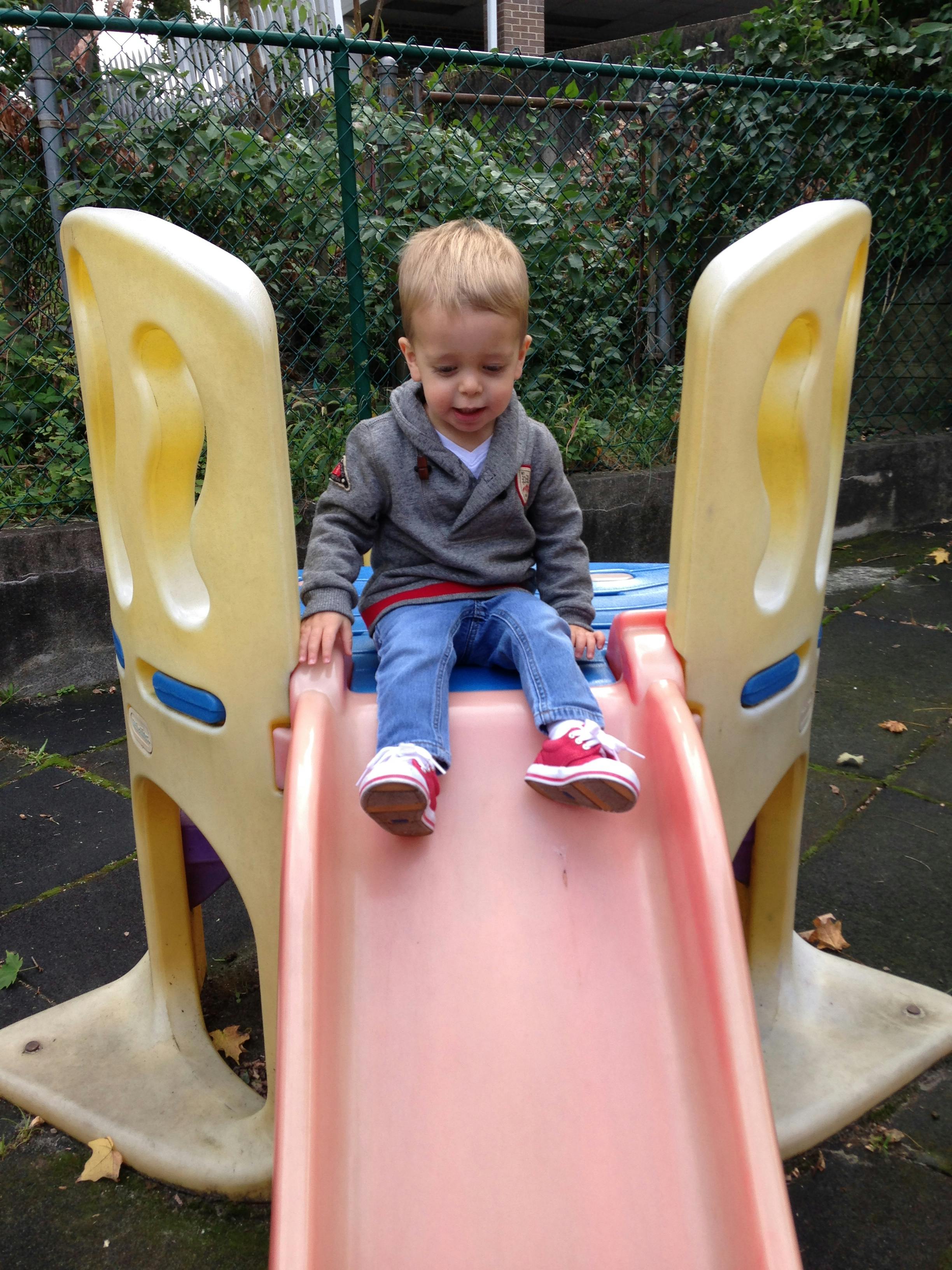 Child sitting at the top of a slide
