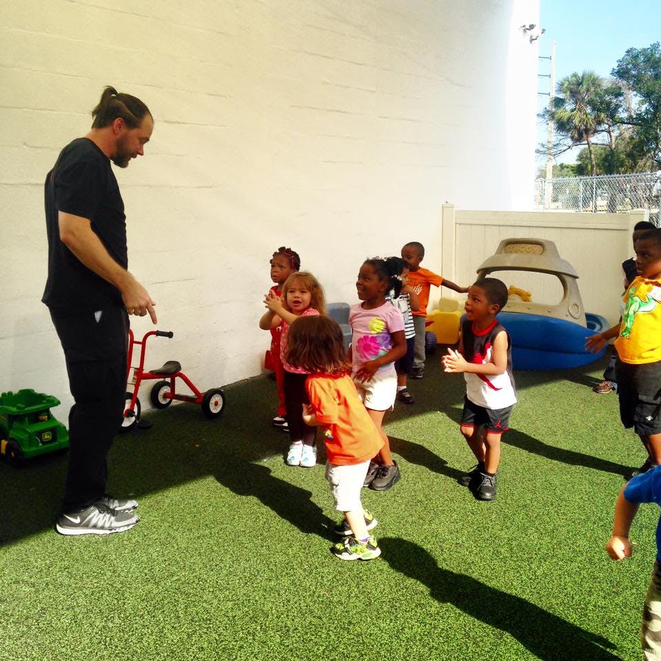 Adult person interacting with a group of children outdoors