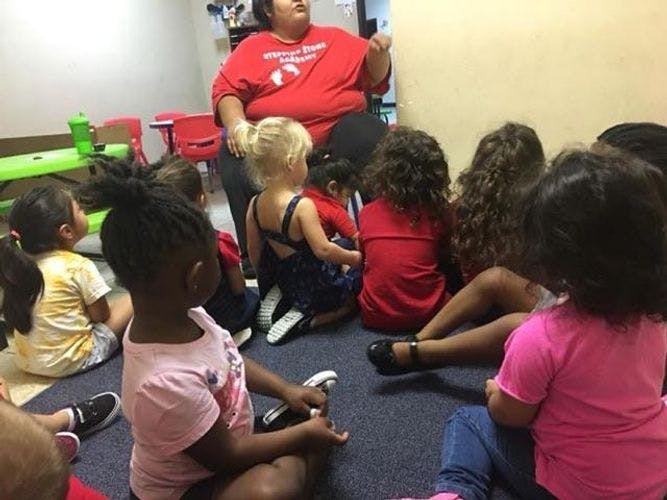 Adult speaking to a group of children sitting on the floor