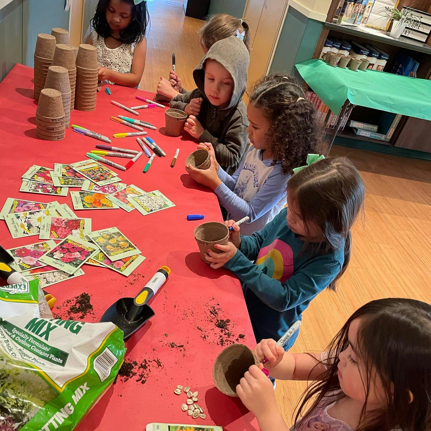 Children decorating small pots at a table