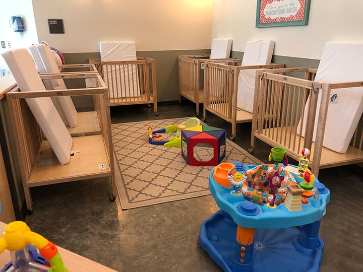 Multiple cribs and baby play items in a room