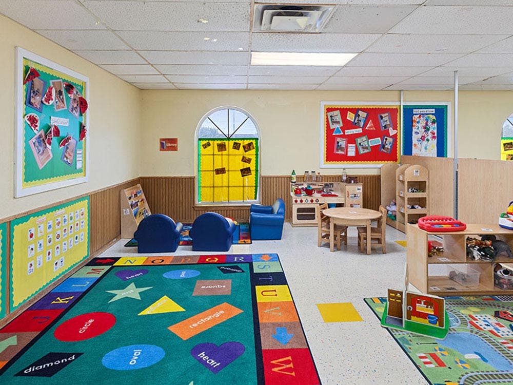 Colorful classroom with rugs, small chairs, tables, and toys