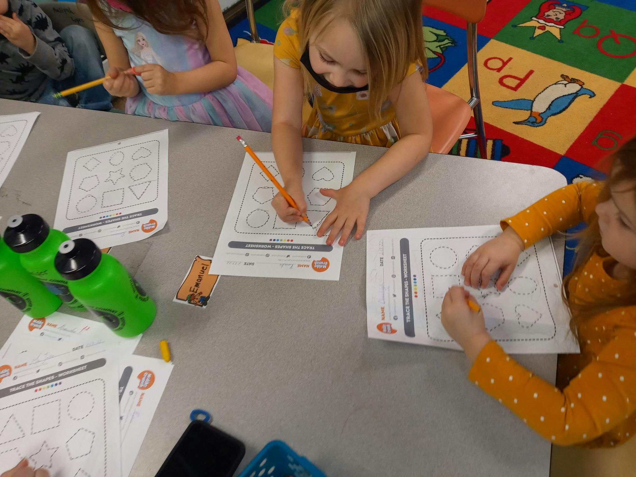 Children writing on worksheets at a table