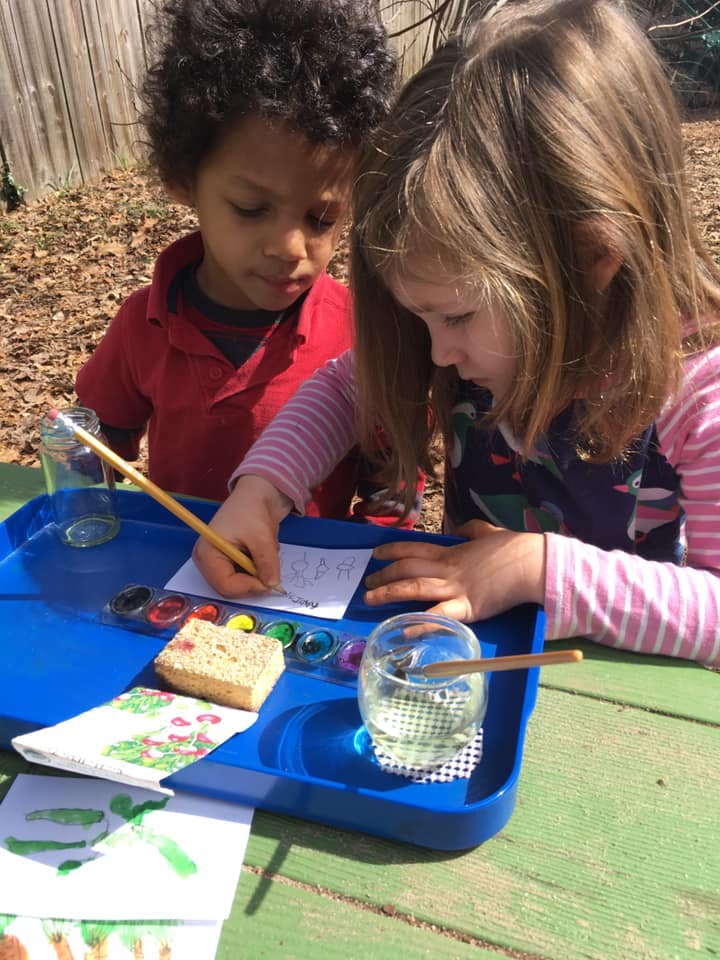 Two children painting outdoors
