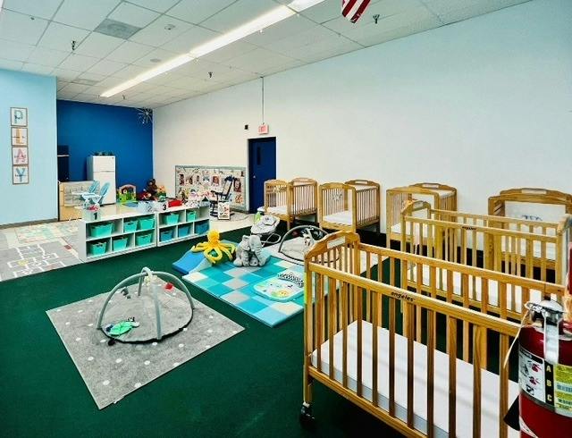 Cribs and play mats with infant toys in a childcare room