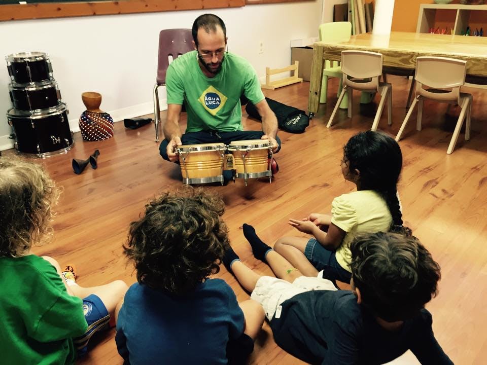 Person playing bongos for a group of children