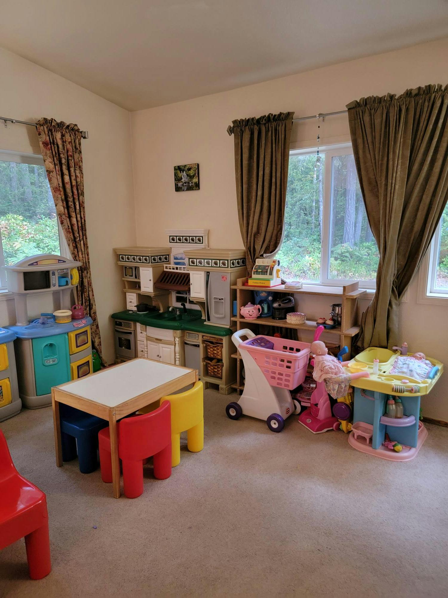 Playroom with toy kitchen, table and chairs, shopping cart, and other toys