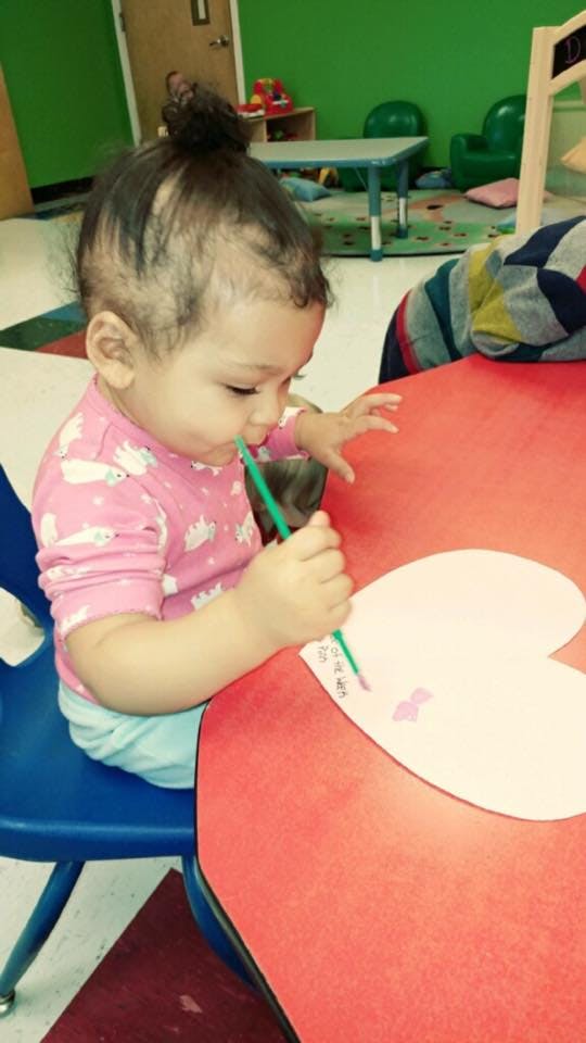 Child painting a heart shape on a red table