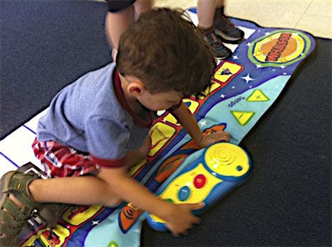 Child playing with a colorful floor mat toy