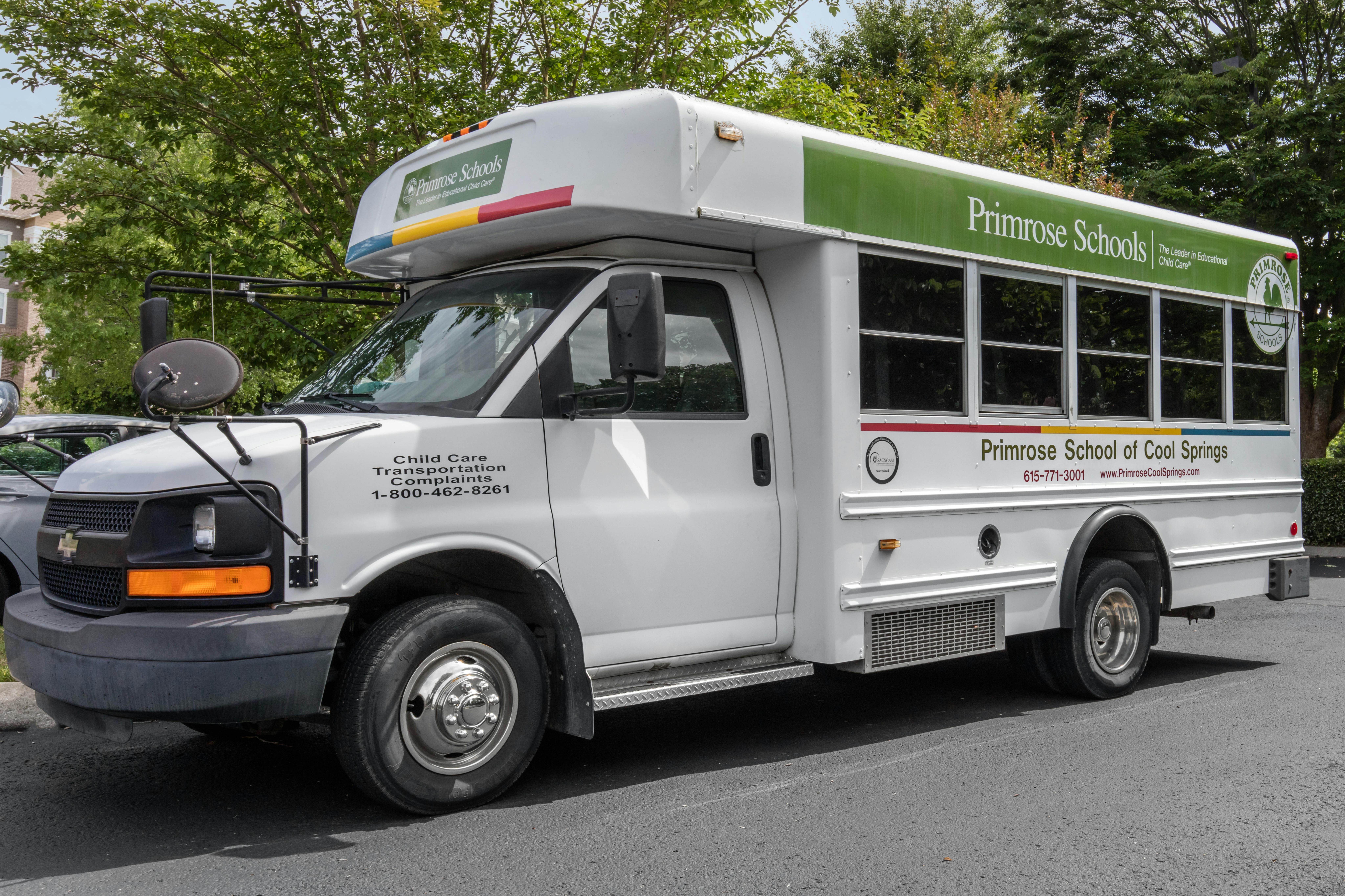 White school bus with "Primrose Schools" logo and text, parked outdoors