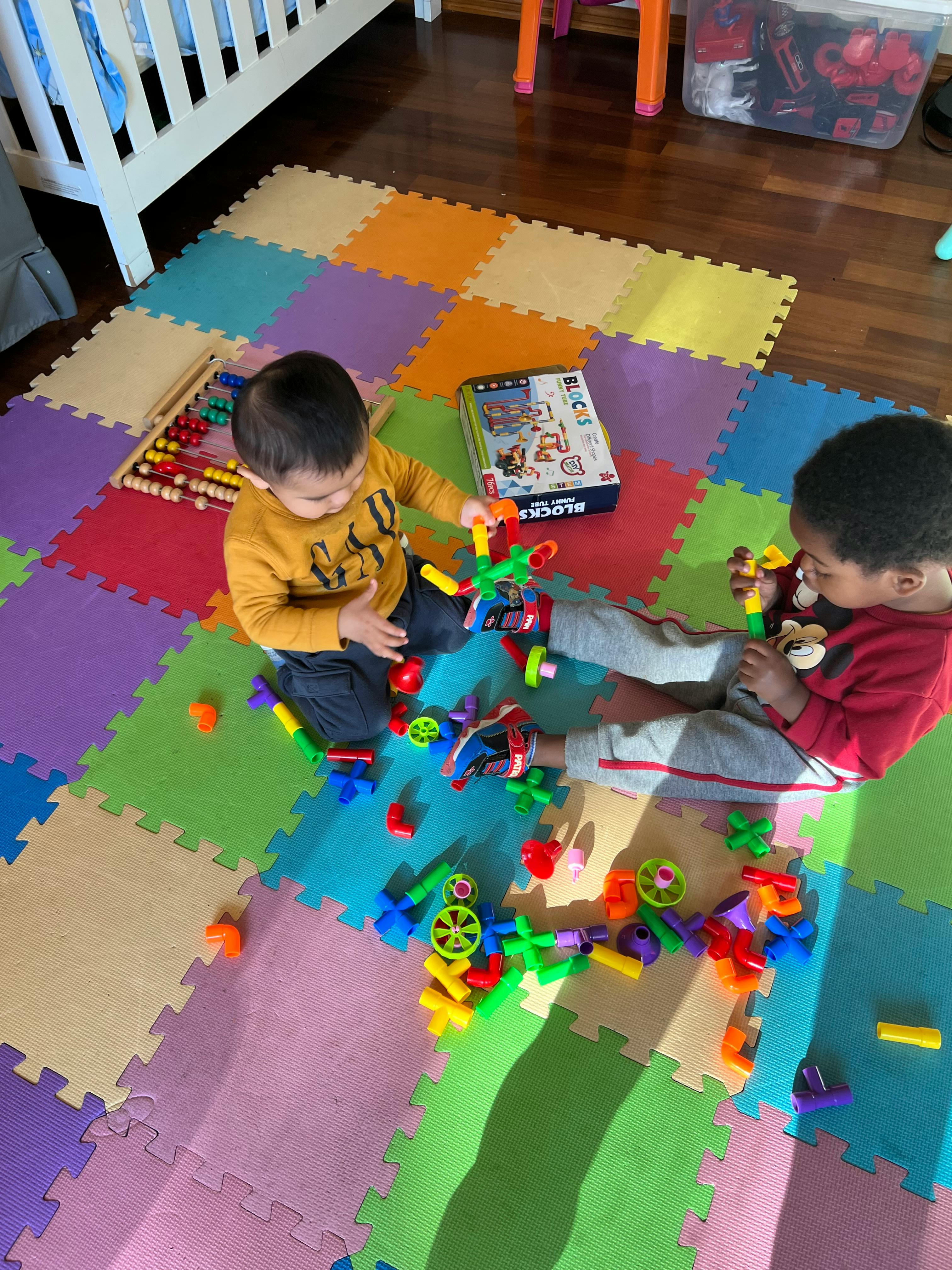 Two children playing with colorful building toys on a mat