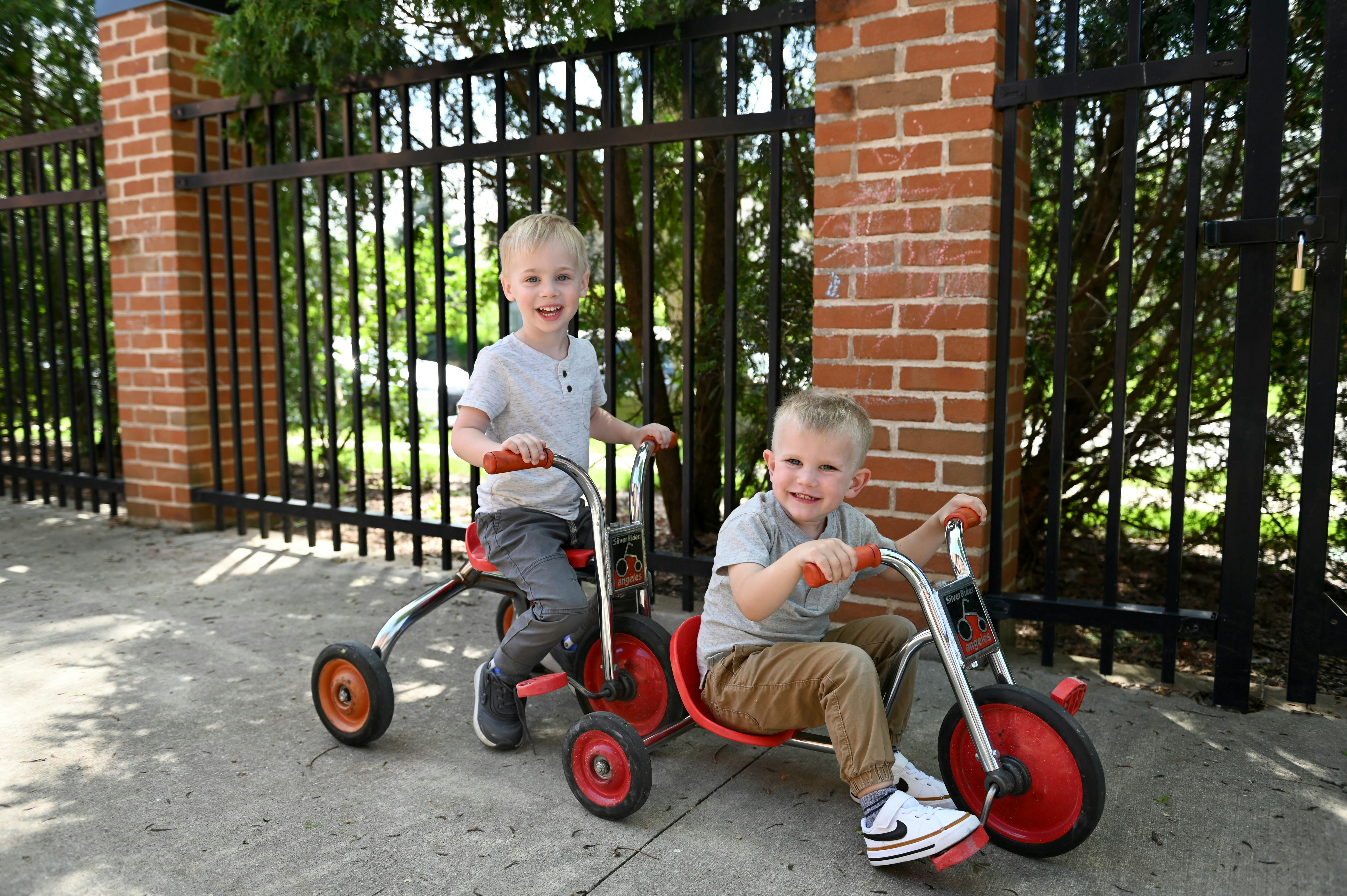 Two children on tricycles outdoors