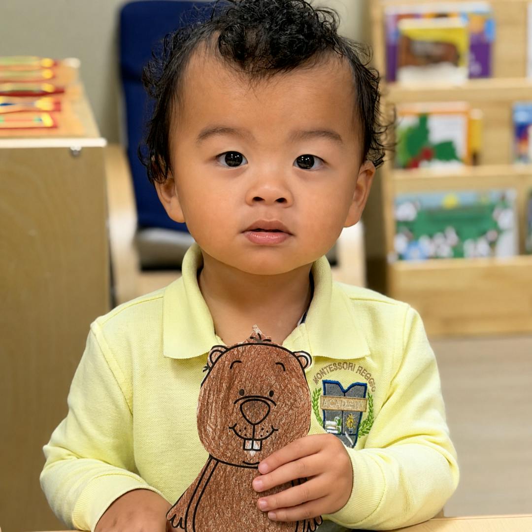 Child holding a brown drawing of a beaver