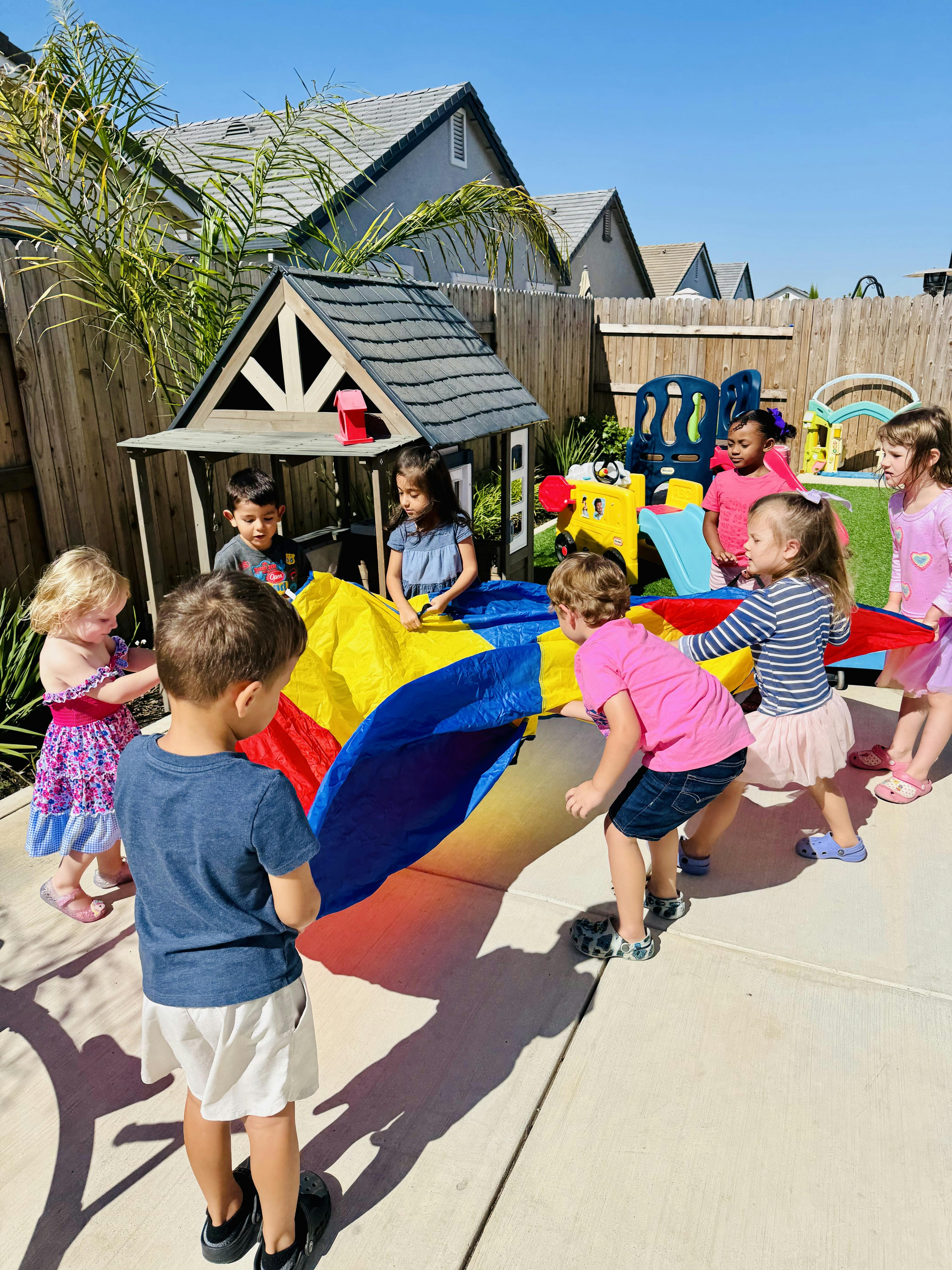 Children playing with a colorful parachute outdoors