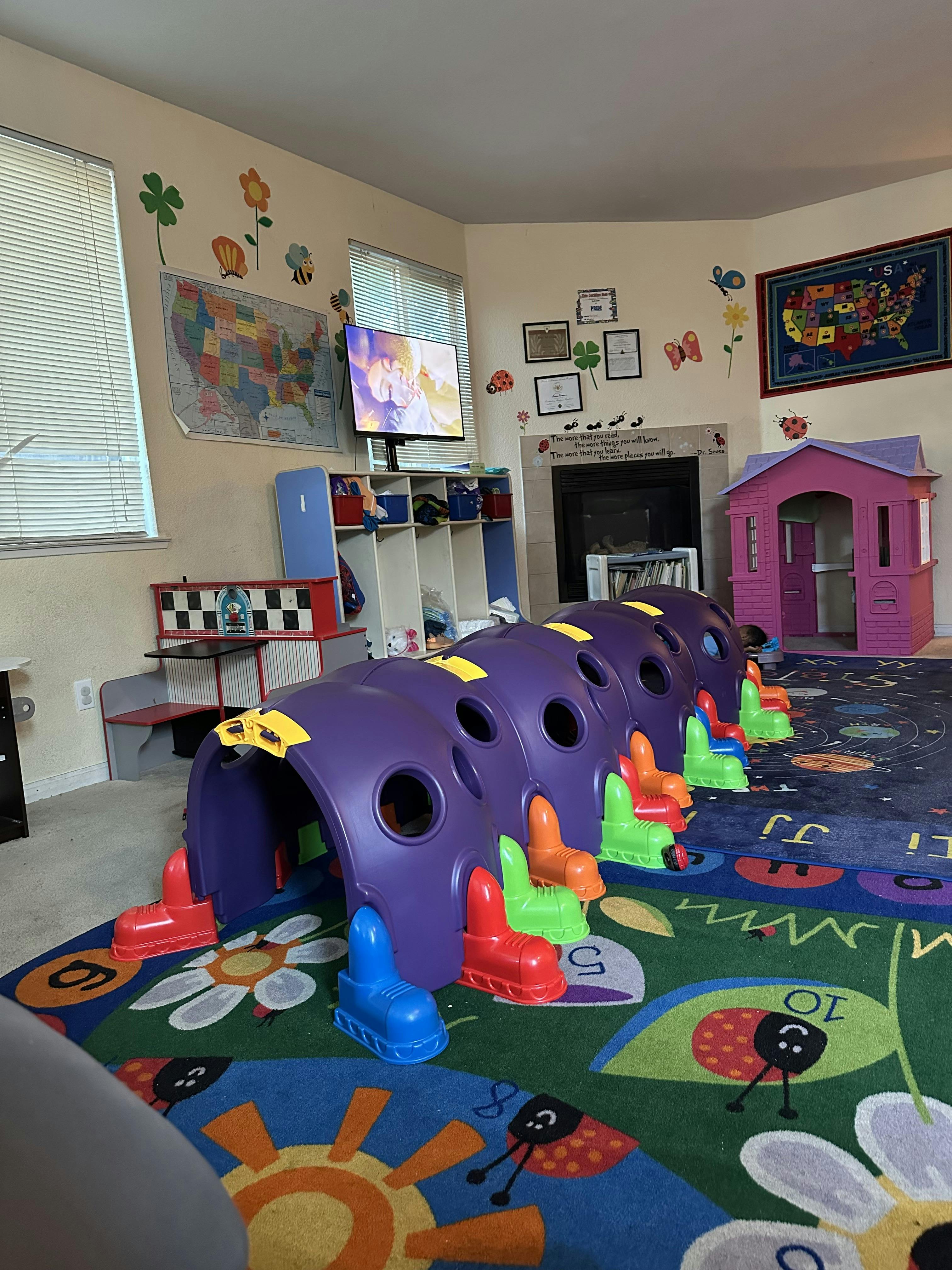 Playroom with a purple caterpillar tunnel and a pink playhouse