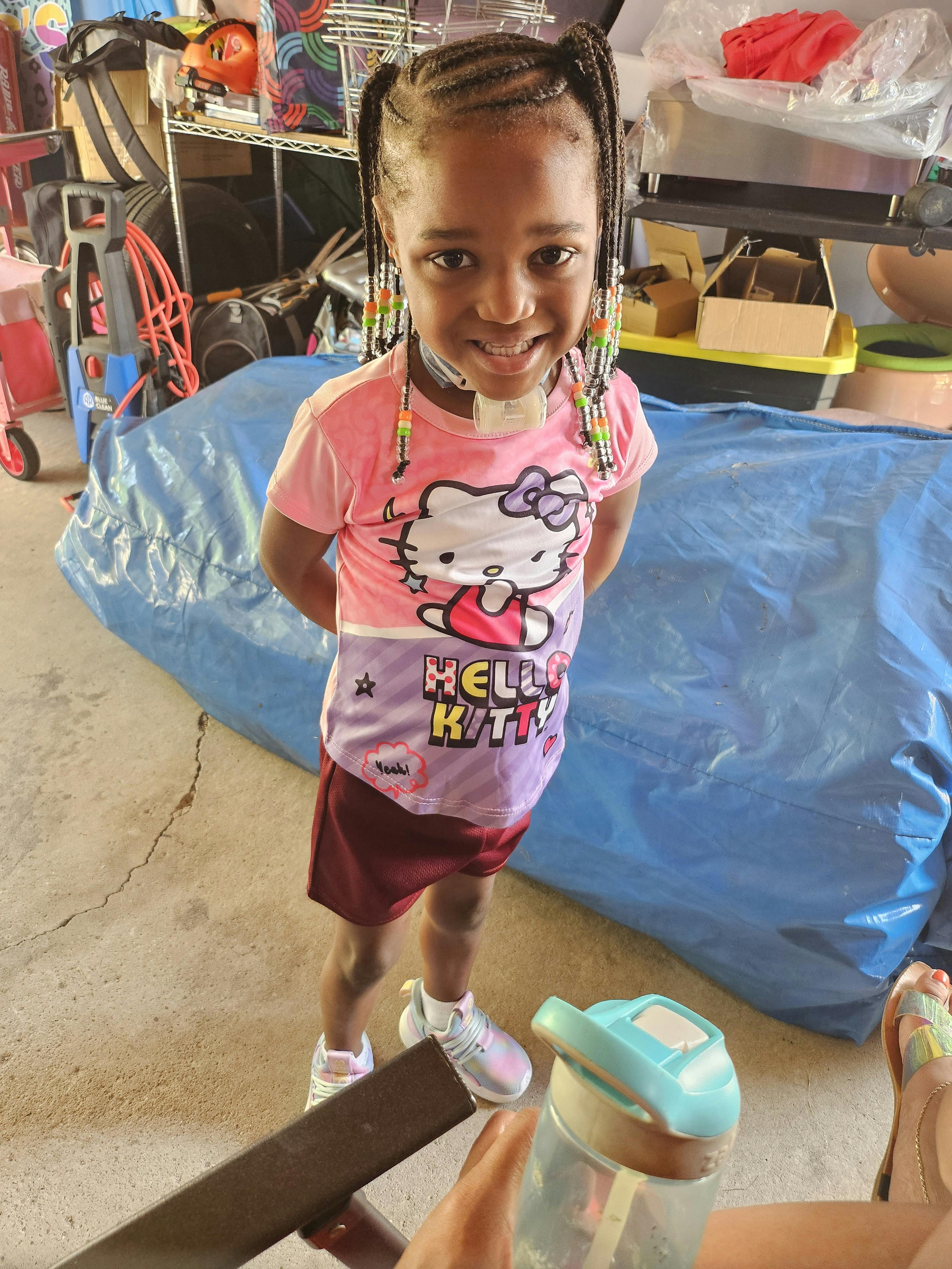Child smiling and looking up, wearing a Hello Kitty shirt