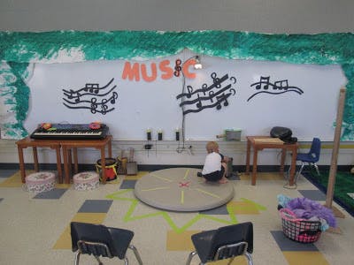 Child playing on a circular mat in a music-themed room