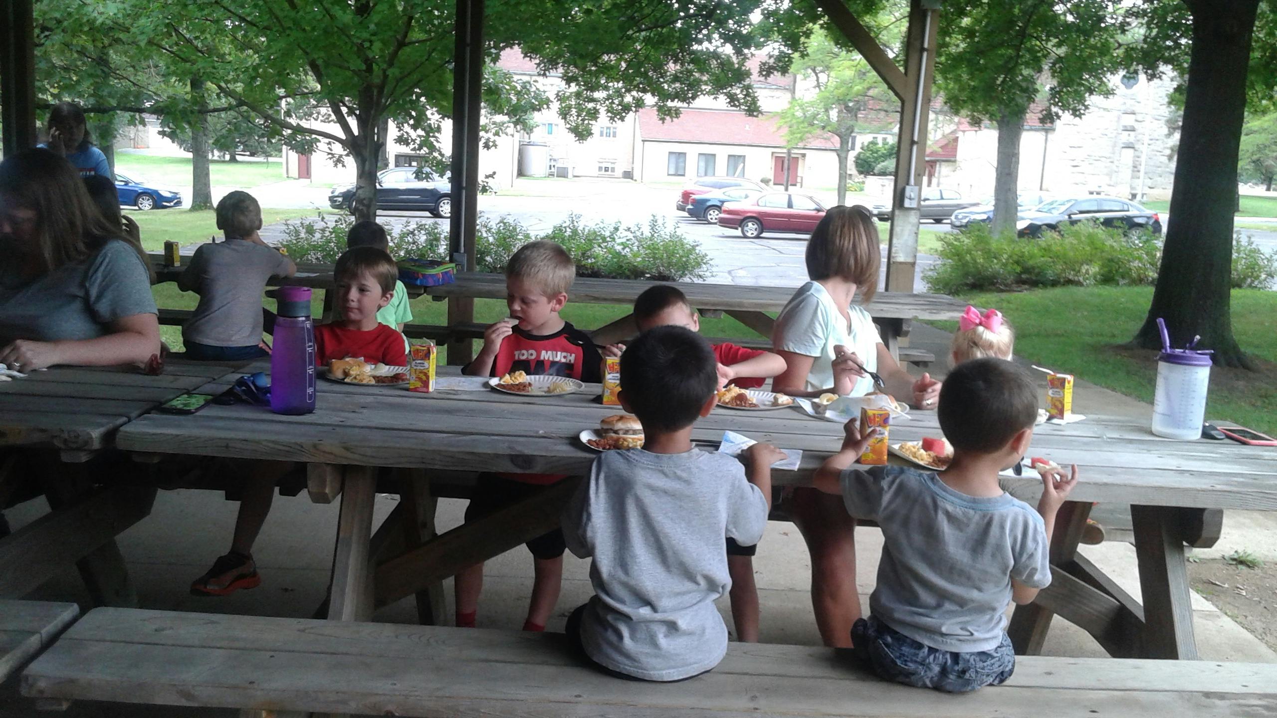 People and children sitting at picnic tables outdoors