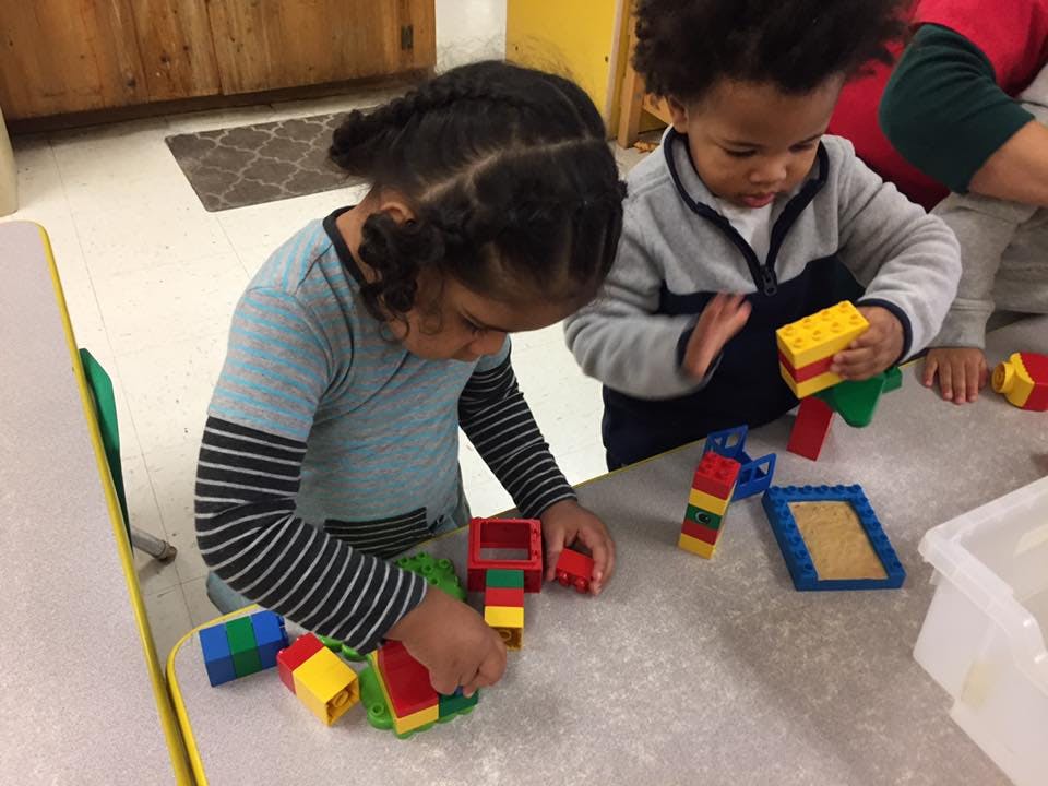 Two children playing with colorful building blocks on a table