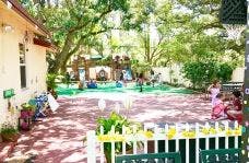 Outdoor play area with a building, trees, and play structures