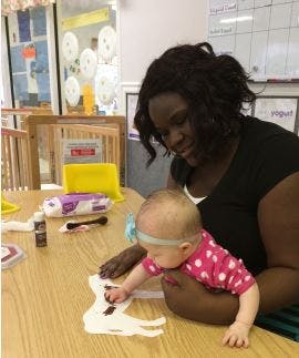 Adult and baby doing an art activity at a table