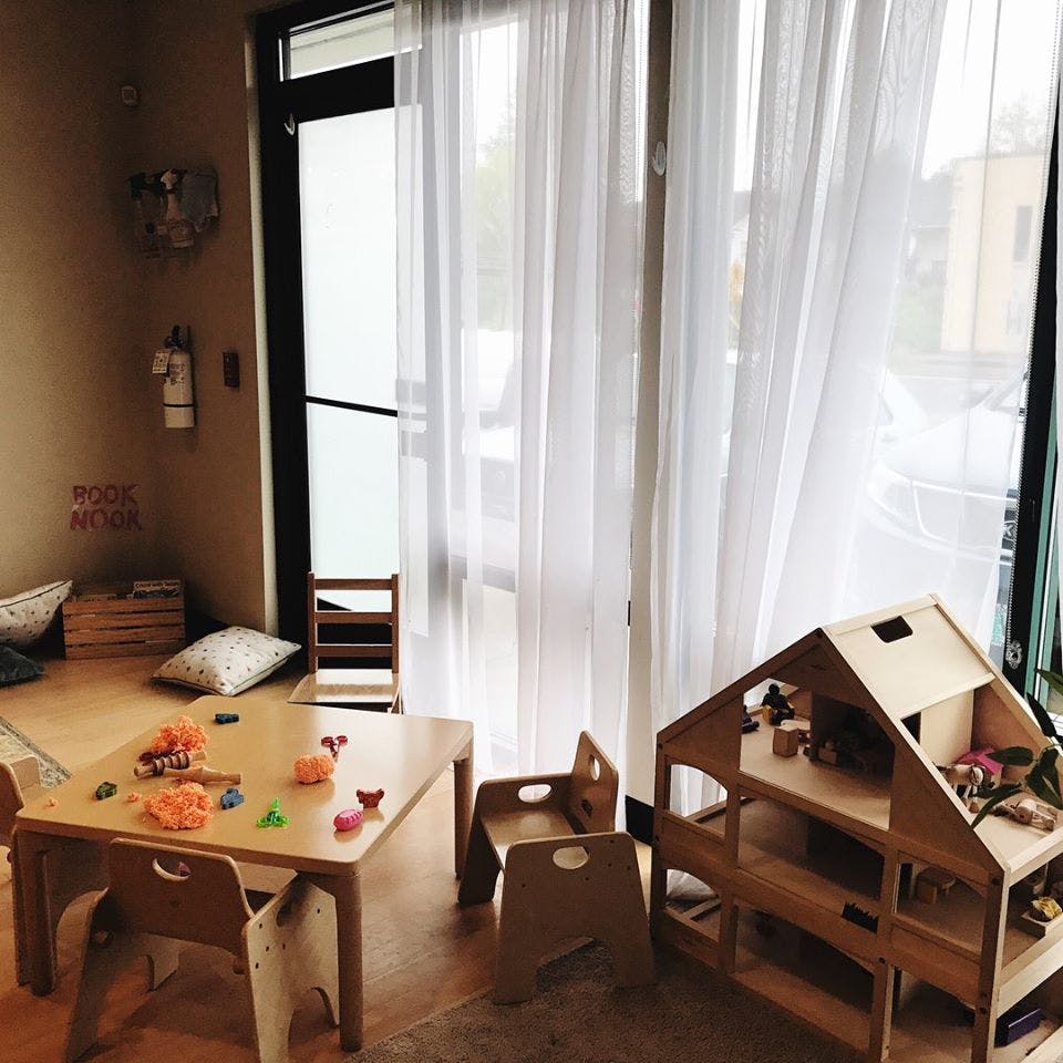 Children's play area with small table and chairs, and a wooden dollhouse